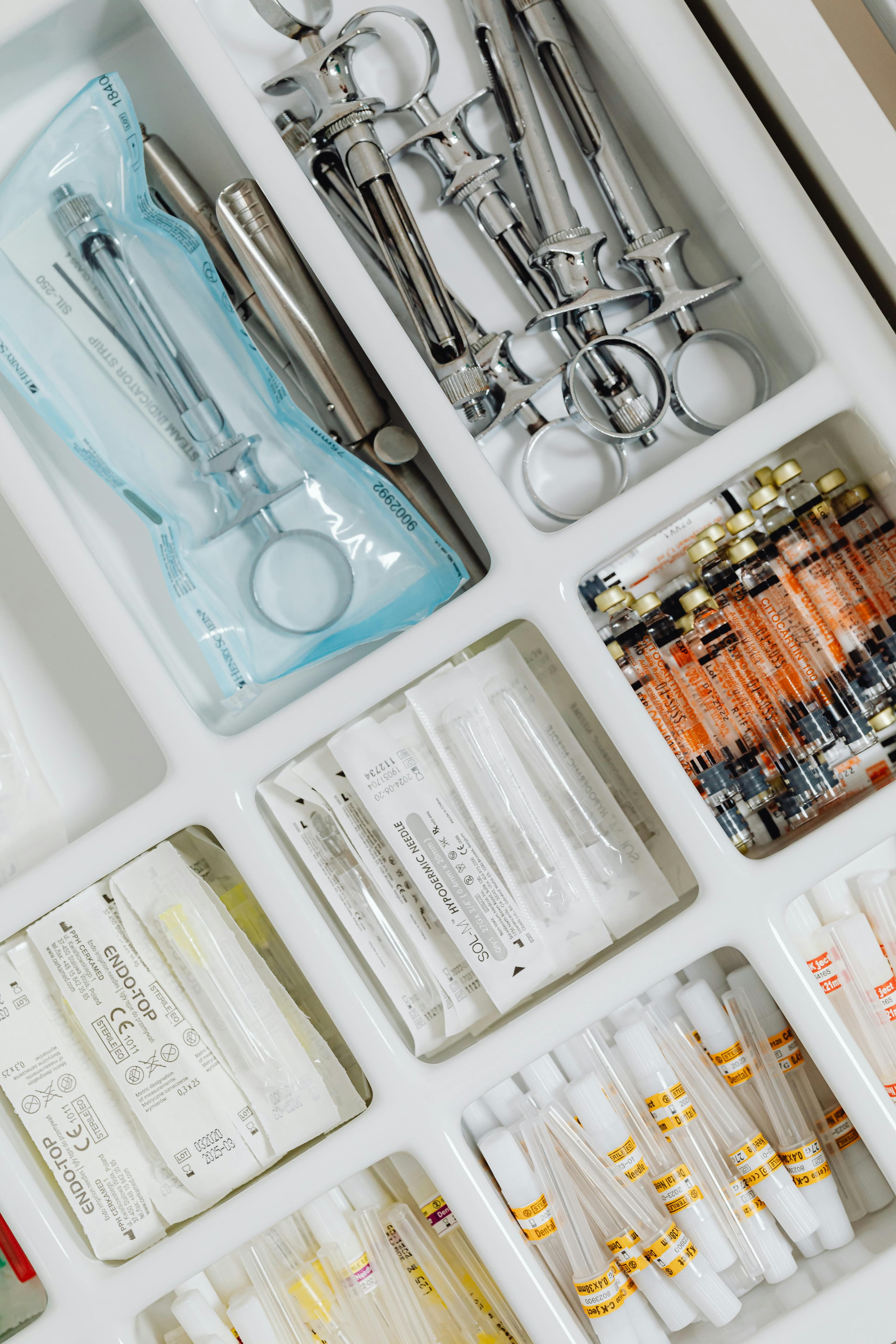 Organized dental tray containing metal syringes, sterile hypodermic needles, and vials of local anesthetic.