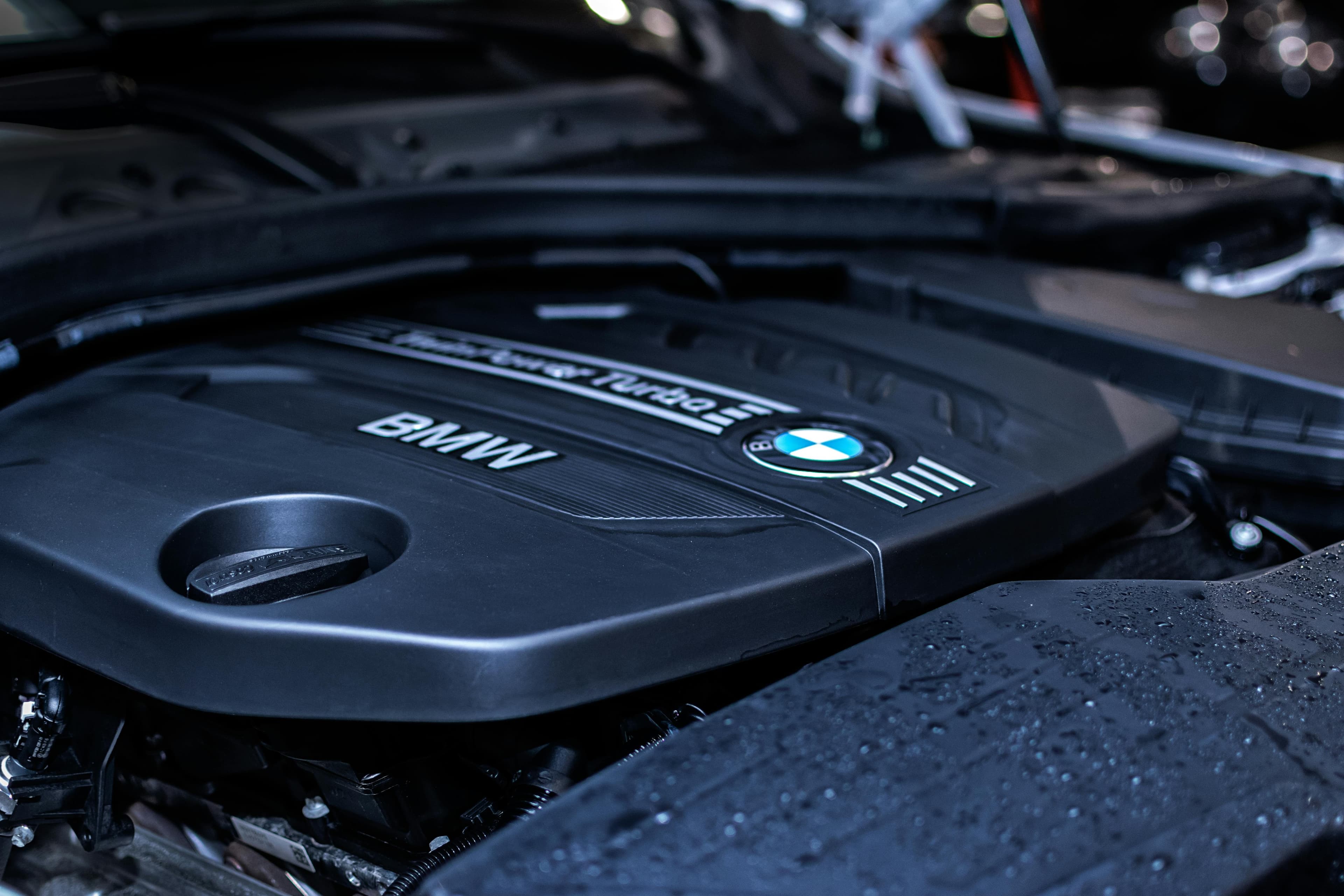 Close-up of a black BMW TwinPower Turbo engine cover featuring the brand logo and name.