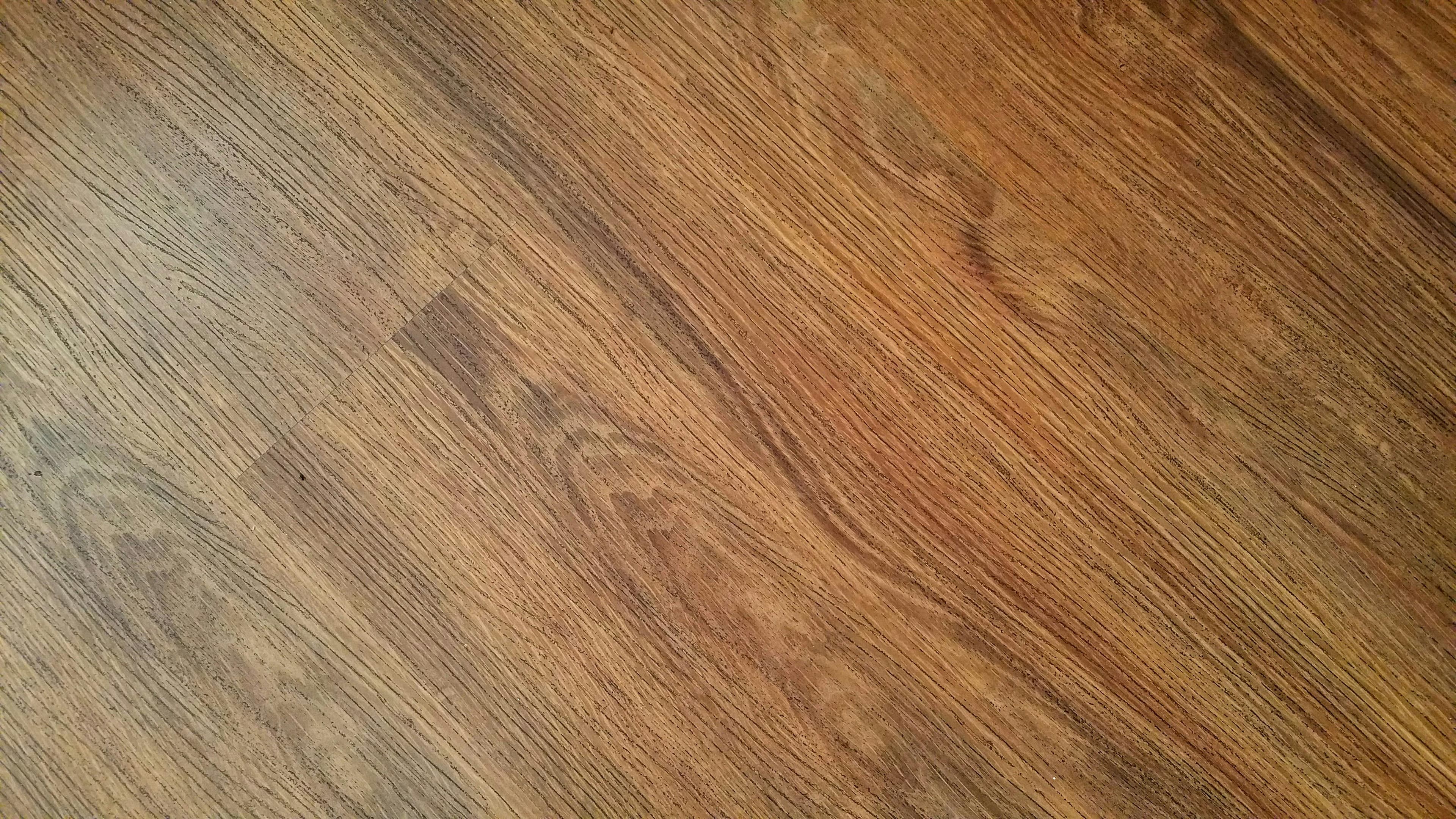 Warm brown wood flooring planks with a visible diagonal grain pattern and subtle seams.